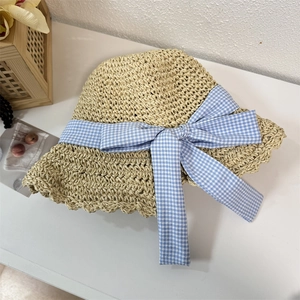 Straw sun hat with wide wavy brim and blue checkered bow for summer beach vacation