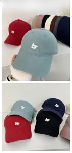 Close-up of cute bear embroidery on various colors of cotton denim baseball caps