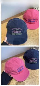 Detail of embroidered Moonmoi Garden text on navy and pink cotton camping caps