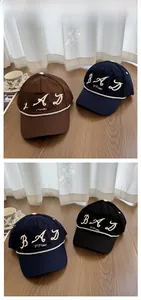 Detail of embroidered letters on brown and navy canvas baseball caps with rope accent
