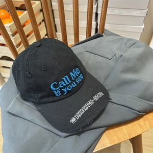 Distressed black cotton baseball cap with blue 3D embroidery on a rustic background