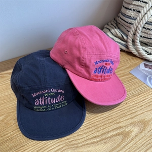 Navy and pink flat bill baseball caps with embroidery on light wood background