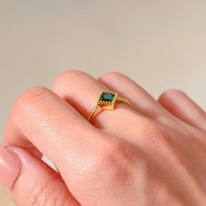 Close-up of a gold ring with square-cut emerald zircon on a model's hand