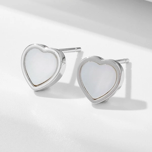 Gros plan de boucles d'oreilles en argent s925 en forme de cœur avec nacre sur blanc
