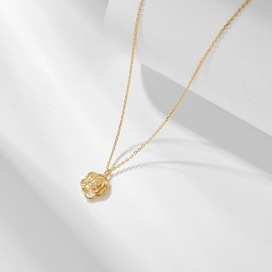 Gros plan d'un pendentif rose ajouré doré avec un petit diamant sur un support blanc