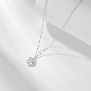 Gros plan détaillé d'un pendentif camélia en argent avec zircon blanc sur une chaîne