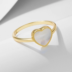 Vue macro d'une bague coeur en argent 925 doré avec incrustation en nacre blanche