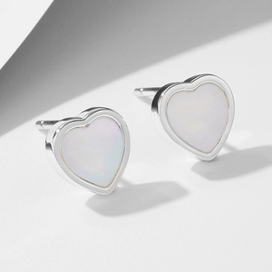 Boucles d'oreilles cœur en argent S925 avec nacre irisante sur un fond blanc minimaliste
