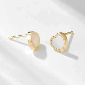 Boucles d'oreilles cœur dorées avec incrustation de nacre sur une surface marbre
