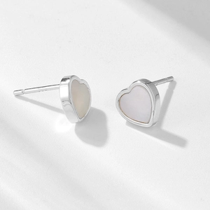 Gros plan de boucles d'oreilles en cœur avec incrustation nacre et métal argenté