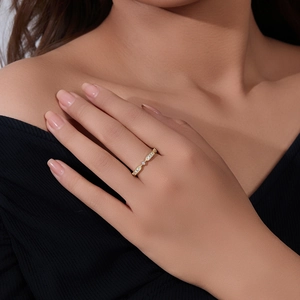 Détail d'une bague géométrique fine en or sertie de diamants portée par un mannequin