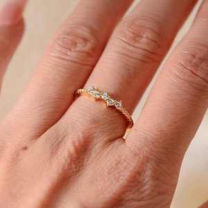 Close-up of gold ring featuring wave-patterned white zircons on model's hand