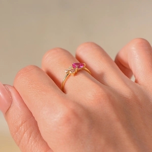 Detailed view of a gold ring featuring a heart-shaped pink stone and small side diamonds