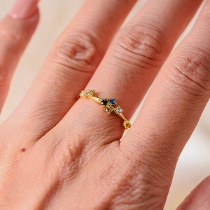 Macro view of gold ring featuring asymmetric rainbow zircon stones on model's hand