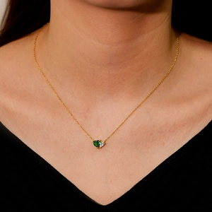 Collana dorata con smeraldo a cuore e ciondolo in zircone a pera su modella