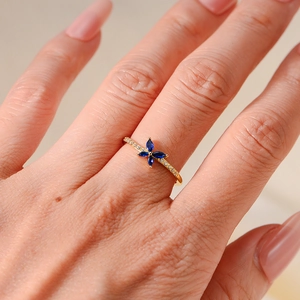 Detailed view of an elegant golden butterfly ring with blue marquise stones and zircon accents