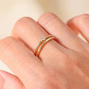 Eleganter goldener Doppelring mit zentralem Zirkon und mikro-gepflastertem Band-Design