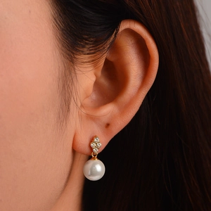 Close-up of S925 silver pearl drop earrings with sparkling zircon clover stud details