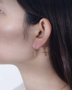 Dettaglio degli orecchini a croce in oro minimalista indossati da una modella