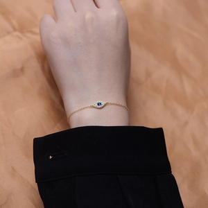 Macro shot of evil eye bracelet with blue center stone and crystals on golden chain