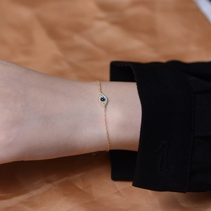 Detail of gold evil eye bracelet with blue zircon and white diamonds on wrist