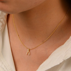Detail of gold wishbone pendant necklace with sparkling zircons on model neck