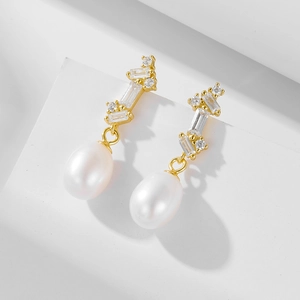 Detailed macro view of S925 silver pearl earrings with zircons on white pedestal