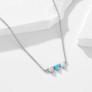 Sterling silver necklace with trio of round blue opal and cubic zirconia stones on white stone