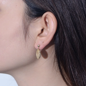 Detail of vintage gold oval Virgin Mary relief earrings worn on model's ear