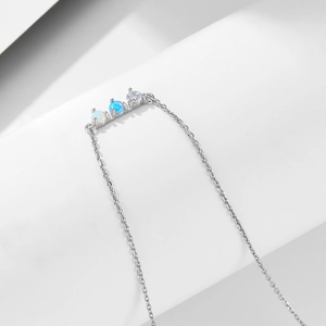 Detail of silver necklace with three-stone pendant featuring opal and round zircon