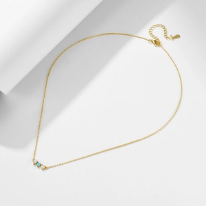 Detail of silver gold-plated chain with opal and blue stone pendant on white board