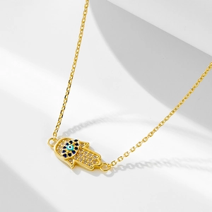 Vue détaillée du pendentif Main de Fatma avec zircons et œil bleu sur chaîne dorée