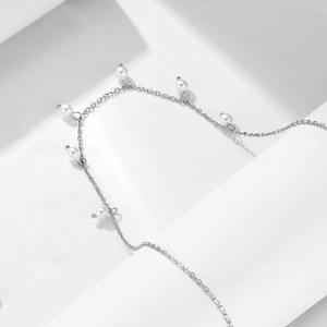 Detailed view of silver necklace with elegant white pearls on minimalist white pedestal