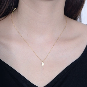 Collier main de Fatma dorée avec pendentif zircon sur un cou de mannequin et col noir