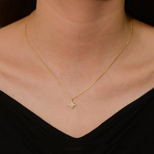 Sparkling gold starburst necklace with crystals worn on a minimalist black V-neck top