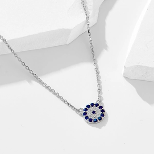 S925 sterling silver evil eye necklace with blue and white crystals on a marble stone