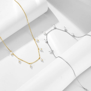 Elegant sterling silver shell pearl necklace in gold and silver finishes on a white pedestal