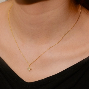 Macro detail of a gold north star necklace with sparkling crystals on a female model