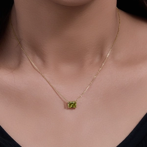 Elegant gold chain necklace featuring a rectangular green zircon pendant on a model