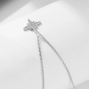 Macro shot of silver eight-pointed star pendant necklace with white cubic zirconia pavé