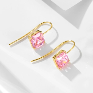 Gros plan de boucles d'oreilles zircon rose avec crochets dorés sur fond blanc