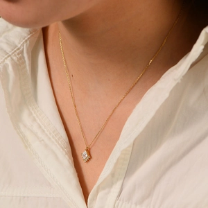 Close-up of a gold geometric diamond pendant necklace with zircons on a model
