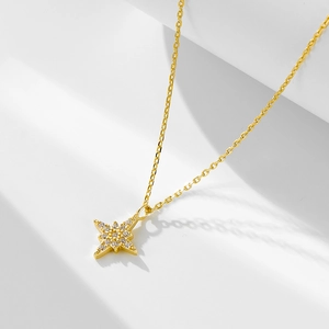 Macro view of gold north star pendant necklace with cubic zirconia on white background