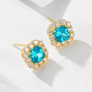 Golden square stud earrings with blue gemstone and white zircon halo on white steps