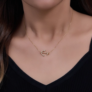Elegant gold anchor pendant necklace on female model wearing a black V-neck top