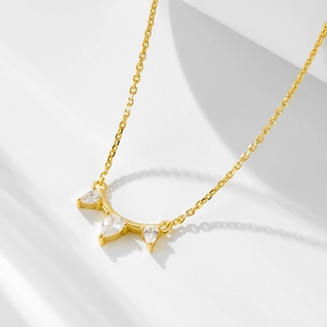 Détail du pendentif doré avec cristaux en forme de poire sur une chaîne fine