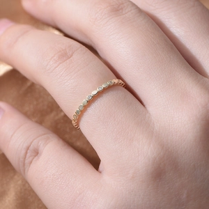 Close-up of minimalist gold zircon ring on model's finger with silk background