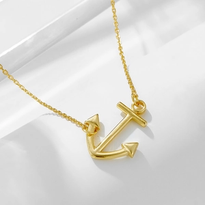 Detailed view of polished golden anchor pendant on fine cross chain necklace