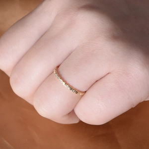 Close-up of a minimalist gold ring with zircon stones worn on a female finger