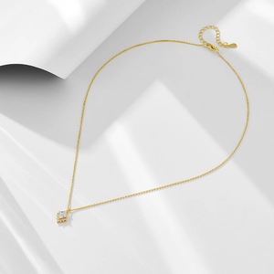 Detail of gold geometric pendant necklace with sparkling cubic zirconia on white background